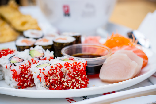 this plate, featuring a medley of salmon and California rolls with sashimi and spy sauce. This close-up captures the vibrant colors and exquisite details that make each bite a culinary masterpiece.