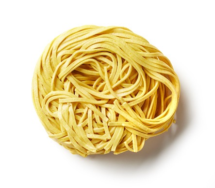 dry uncooked yellow asian egg noodles isolated on white background, top view