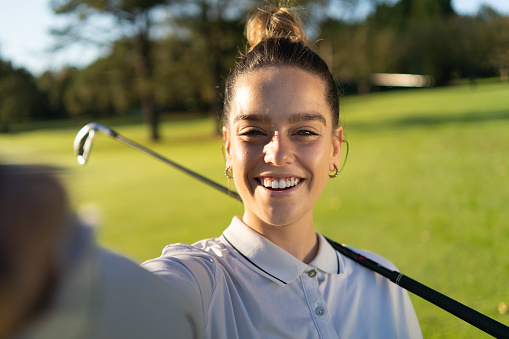Personal perspective of a female golfer smiling while taking a selfie