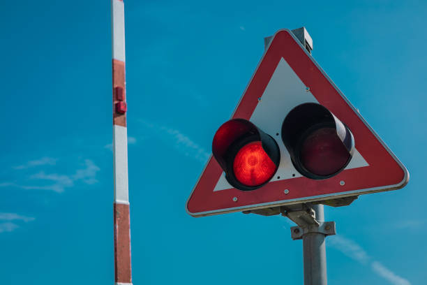 Train lights or train signal with barrier behind it waiting to be lowered when train approaches. Train warning lights are blinking. Beware of train.