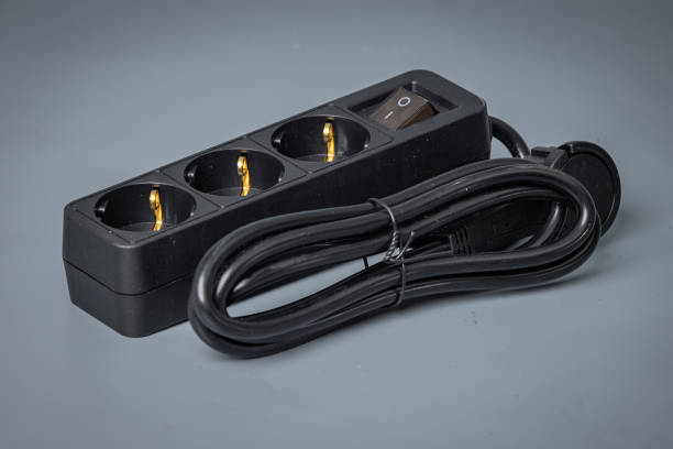 istock Electrical cord with three outlets and a power switch. Brand new black power cord with plugs, isolated on gray. 1815285108