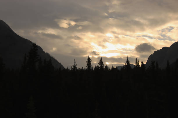Clouds in front of the sun behind the mountains