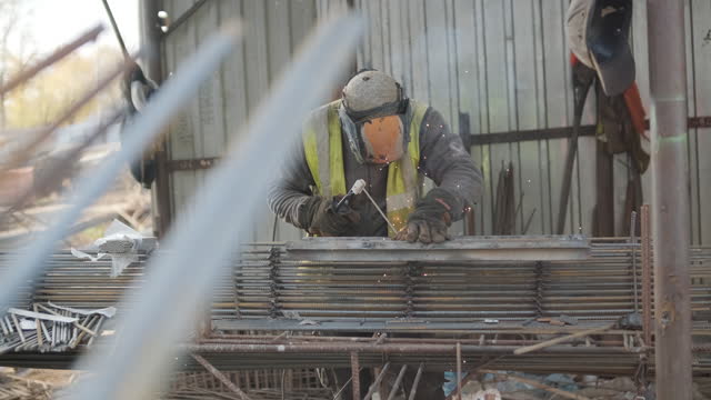 Construction worker welding metal rebar for the pouring of monolithic structure
