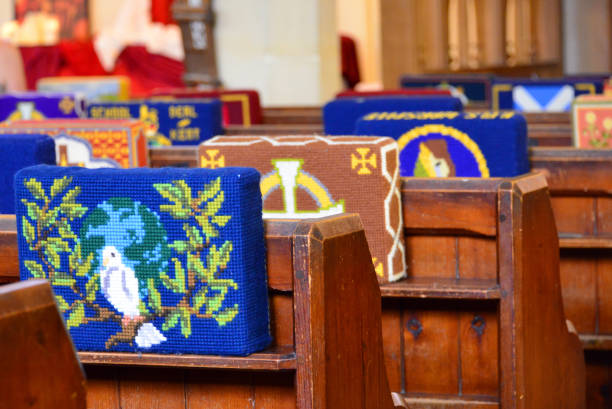 Kneeling cushions -  tapestry kneelers on pews, England, UK Marazion, Cornwall, England, UK: tradtional English tapestry kneeling cushions resting on the pews - a kneeler is a cushion used for resting in a kneeling position during Christian prayer (also called a tuffet, hassock, or genuflexorium) - All Saints Church (Church of England) - Victorian Church, completed in 1861. kneelers stock pictures, royalty-free photos & images