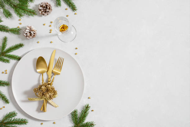 istock Christmas table setting with fir branches, golden decorations and cutlery on white background with copy space. New Year dinner. Top view, flat lay. 1815386638