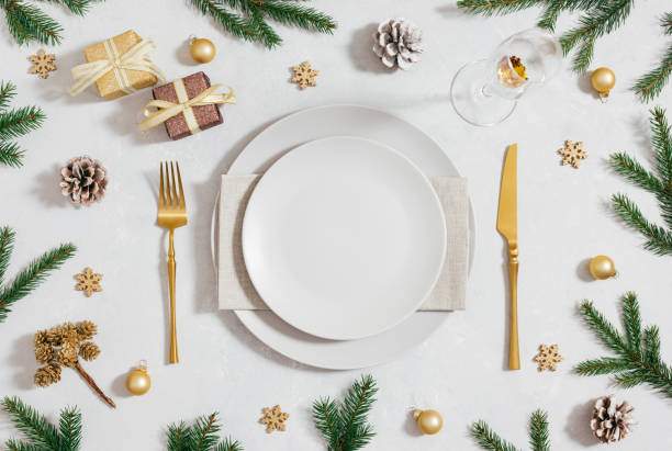 Empty beige plate with Christmas decorations and fir branches on white background. New Year table setting. Top view, flat lay.