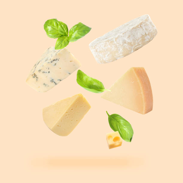 istock Different kinds of cheese and basil leaves falling on beige background 1815390371