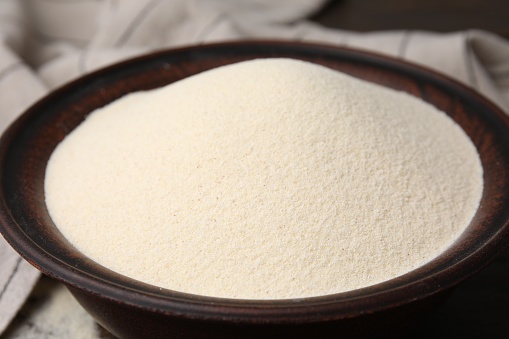 Uncooked organic semolina in bowl on table, closeup