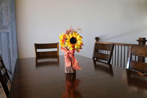 Fall harvest flower decor decorations centerpiece on dark wood kitchen dining room table with sliding barnwood door in background
