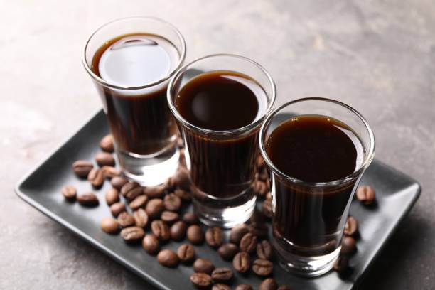 istock Shot glasses with coffee liqueur and beans on light grey table, closeup 1815425232