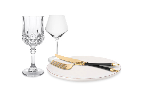 Clean plate, cutlery and glasses on white background