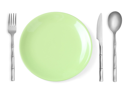 Empty light green plate with fork, knife and spoon on white background, top view