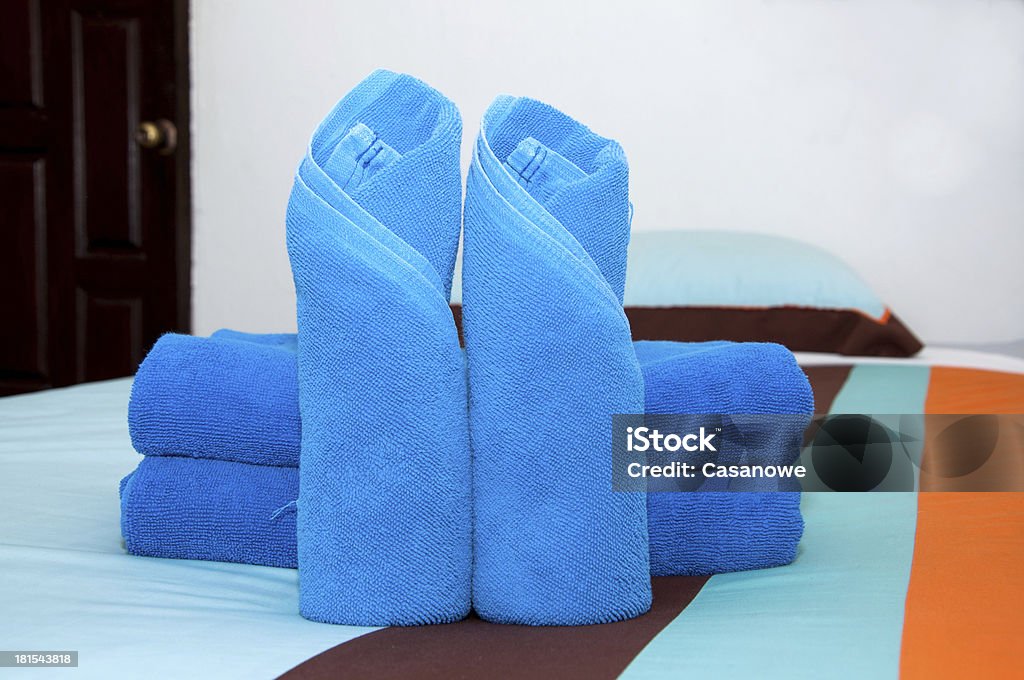 Niebieski ręcznik roll jest umieszczany na łóżku. - Zbiór zdjęć royalty-free (Bawełna)
