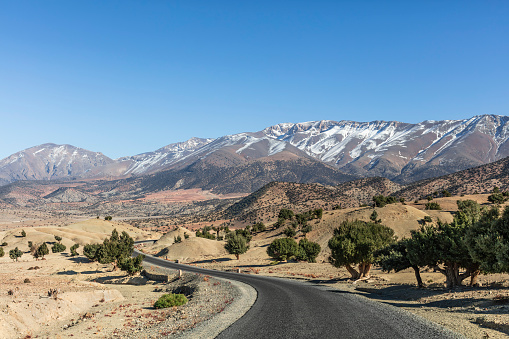 Road winding trough a  snowcapped mountain valley in the Atlas mountains in Morocco