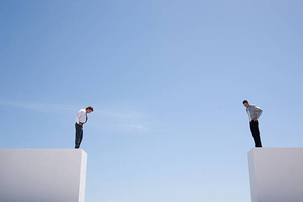 empresarios de pie en pared, mirando hacia abajo - dividing fotografías e imágenes de stock