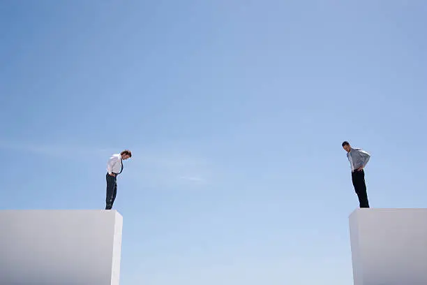 Photo of Businessmen standing on wall looking down 