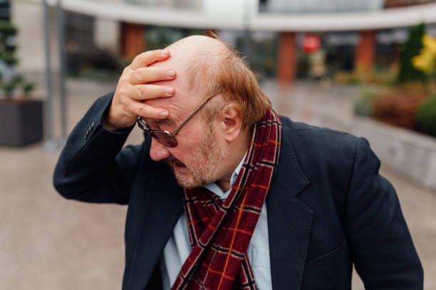 gesundheitsfürsorge alternde männer quälende kopfschmerzen erfahrung in den straßen der stadt - arthritis senior adult rheumatoid arthritis sadness stock-fotos und bilder