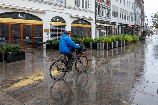 Odense, Denmark Oct 30, 2023 A bicyclist in the rain bikes on Vestergade.
