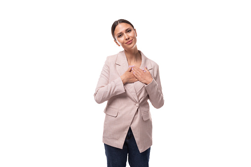 young stylish brunette woman dressed in a beige jacket and jeans on a white background.