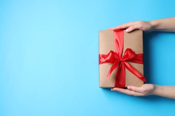 istock Woman with gift box on light blue background, top view. Space for text 1815512482