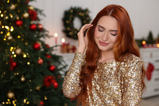 Beautiful young woman in room decorated for Christmas
