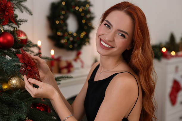 istock Happy young woman decorating Christmas tree at home 1815514639