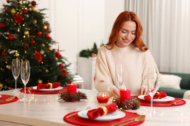 istock Beautiful young woman setting table in room decorated for Christmas 1815515721