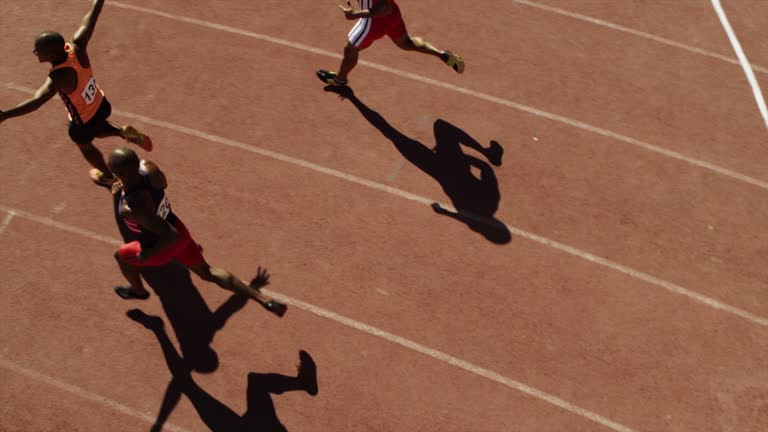 Male sprinters crossing finish line