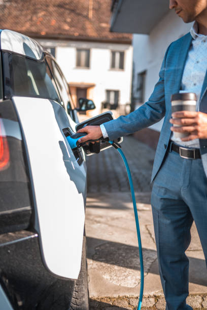 istock White Electric Car Being Charged by Asian Man 1815522957