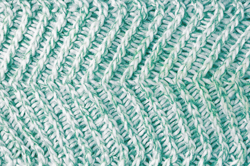 Jersey textile background , green white melange knitted wool fabric. Woolen knitwear, sweater, pullover surface texture, textile structure, cloth surface, weaving of knitwear material