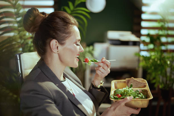 istock smiling modern woman worker in modern green office eating salad 1815540384