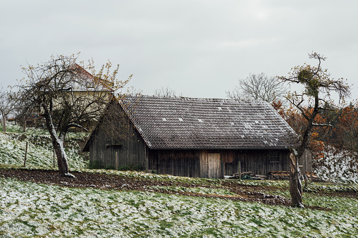 The first snow and a barn in the village. Southern Germany, real photo