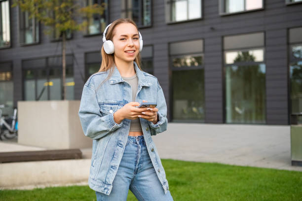 istock A cheerful young lady gazes into the camera while clutching her phone 1815549313