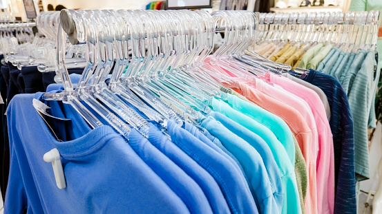 Photo of a colourful t-shirts display in a clothing store.