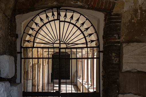 Wrought iron closed gate heading to arched hallway with columns on both sides