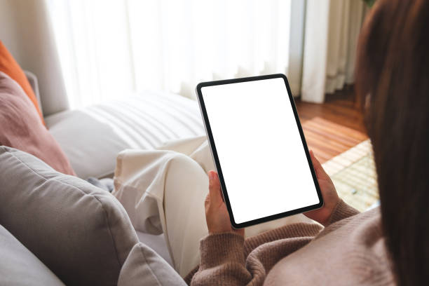 istock Mockup image of a woman holding digital tablet with blank desktop screen while sitting on a sofa at home 1815653275