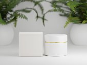 Glossy cream jar with packaging box on a white background with fern plants