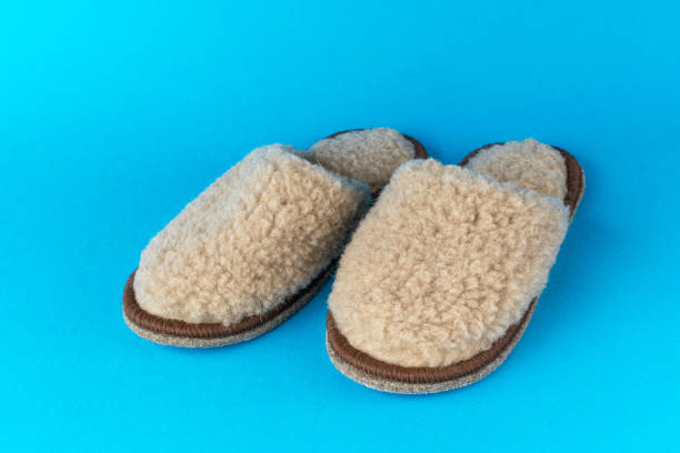 istock Comfortable beige slippers on a blue background. 1815707388