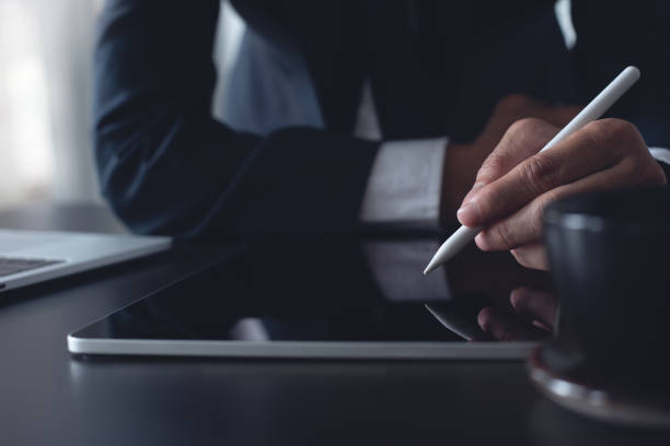 istock Close up, businessman using stylus pen signing e-document on digital tablet at office, E-signing, electronic signature concept. Business man online working on computer devices on office desk 1815750749