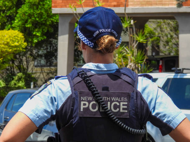 Female NSW Police Officer A Senior Constable of the New South Wales Police in attendance at the site of a traffic accident involving several cars and a scooter. She is looking in the direction of the damaged cars and scooter. This image was taken near the corner of Dudley Street and Bondi Road on a sunny afternoon on 26 November 2023. female police officer stock pictures, royalty-free photos & images