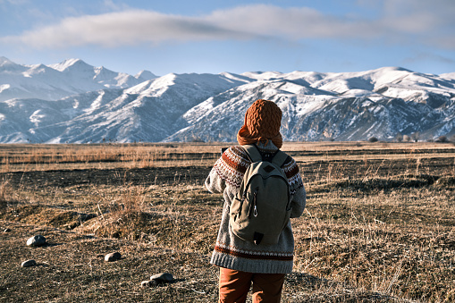 Single woman of 45 is hiking in winter fields in Central Asia and looking at mountain views