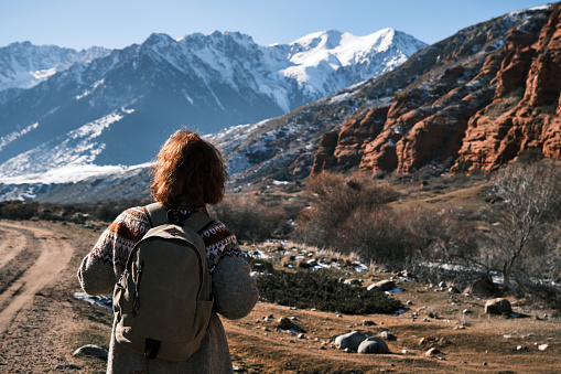 Cheerful woman of 45 is enjoying her hiking on mountain riverbank in winter