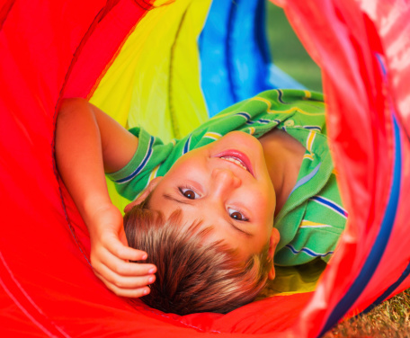 Cute Young Boy Playing Outside in Colorful Tunnel