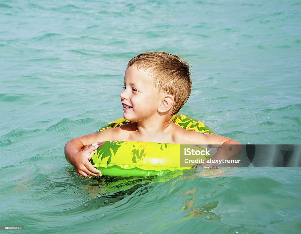 Счастливый мальчик, наслаждаясь плавательный в море с резиновым кольцом - Стоковые фото Веселье роялти-фри