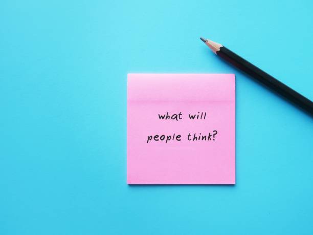 istock Pink note on blue background with handwriting text WHAT WILL PEOPLE THINK? means suffering anxiety around being judged, fear of feeling criticised by others, approval addiction or seeking 1815865037