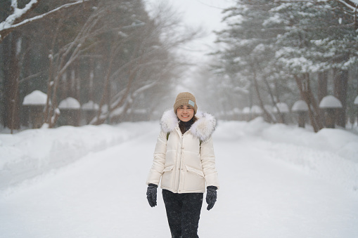 happy Traveler with Sweater and backpack walking on snow covered forest in frosty weather. Winter Travel, Adventure, Exploring and Vacation concept