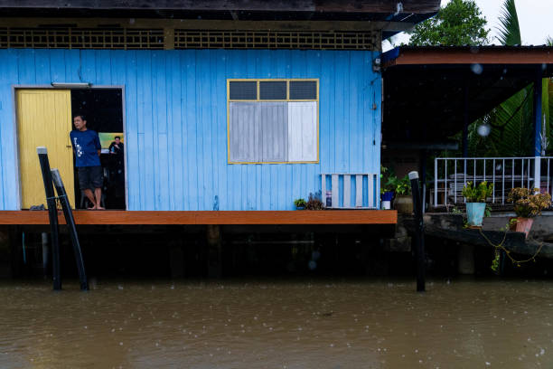 Someone stands on their porch with a TV playing in the background as flood water from the Tapi River approaches during heavy rainfall in Surat Thani, Thailand on November 27, 2023. Heavy rain and flooding take place in Surat Thani, Thailand, a tropical area increasingly affected by climate change during the south's rainy season.