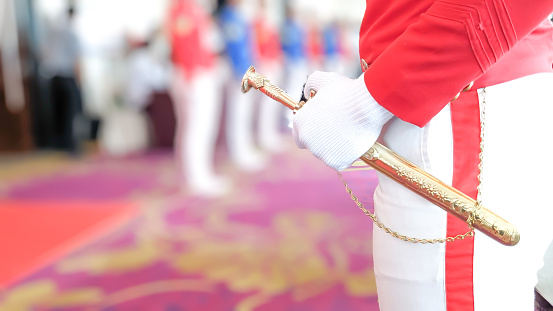 Selective focus of young cadet's hand holding the decorative stainless steel ponyard sword with golden coated eagle head on a ceremony. Vocational academy and Patriotism concept