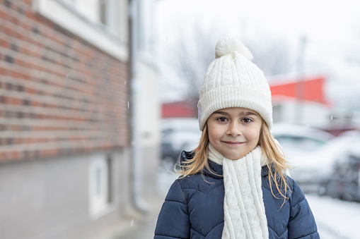 Girl in warm clothing shaking from cold outdoors on a freezing winter day.