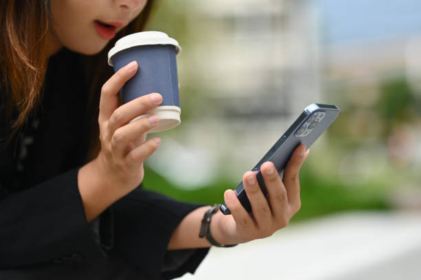 istock Young woman with take away coffee using mobile phone outside office building on sunny day 1815993109